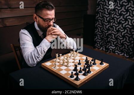 Pensive male chess player in glasses thinking about game strategy. Intelligence competition concept Stock Photo