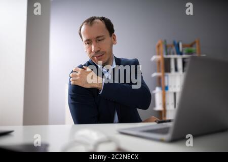 Young Businessman Using Computer Suffering From Shoulder Ache Stock Photo