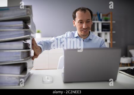 Businessperson Pushing Paper Documents Away And Working With Digital Documents On Computer Instead Stock Photo