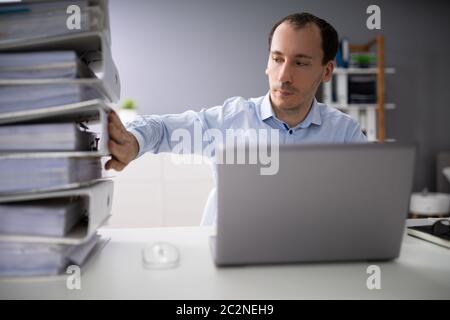 Businessperson Pushing Paper Documents Away And Working With Digital Documents On Computer Instead Stock Photo