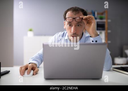 Shocked Businessman Looking At Laptop Screen In Office Stock Photo