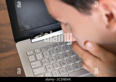 Man Looking At Damaged Laptop Computer With Broken Screen Attachment Stock Photo