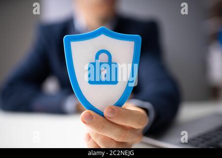 Close-up Of A Businessperson's Hand Holding Blue Shield Security Icon Stock Photo