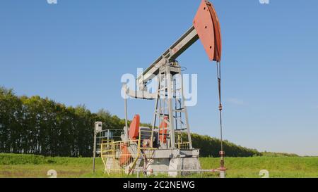 Operating oil and gas well in oil field, profiled against the blue sky Stock Photo