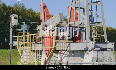 Operating oil and gas well in oil field, profiled against the blue sky Stock Photo