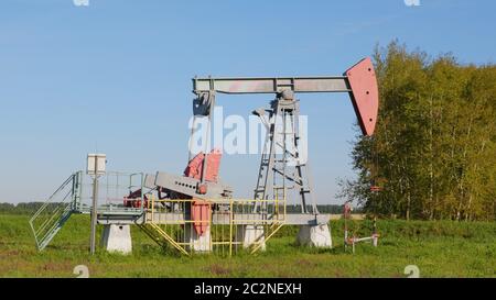 Operating oil and gas well in oil field, profiled against the blue sky Stock Photo