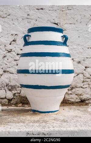 Old blue and white amphora lay on the ground in front of a white wall on the island of Crete Stock Photo
