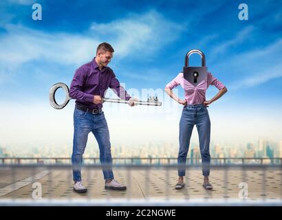 Man holds large key and woman with keyhole instead of a head, cityscape on background. Couple relationship concept Stock Photo