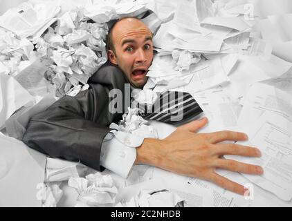 Businessman sinking in heap of documents and asking for help Stock Photo