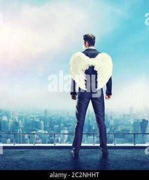 Businessman with angel wings on his back standing on the top of the building Stock Photo