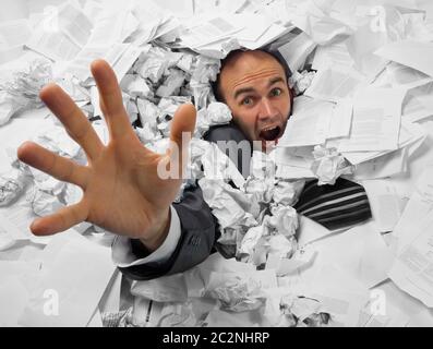 Businessman sinking in heap of documents and asking for help Stock Photo