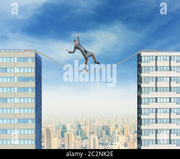 Businesswoman balancing on the rope between two high builgings against the city Stock Photo