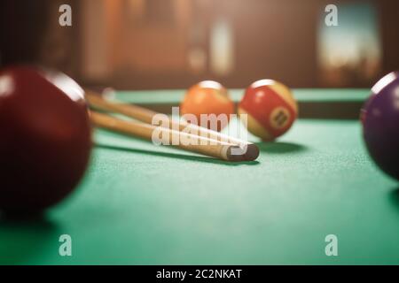 Two cues and spheres on green cloth of a billiard table. Nightlife. Stock Photo