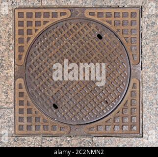 Old rusty sewer hatch on an old metal plate. View from above. Stock Photo