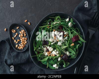 Beetroot, aragula and soft cheese salad over black background. Top view or flat lay. Copy space for text. Idea and recipe for healthy vegetarian salad Stock Photo