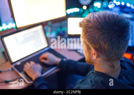 Programmer using laptop and PC, information technology. IT-manager at his workplace, professional coding and encryption, network security Stock Photo