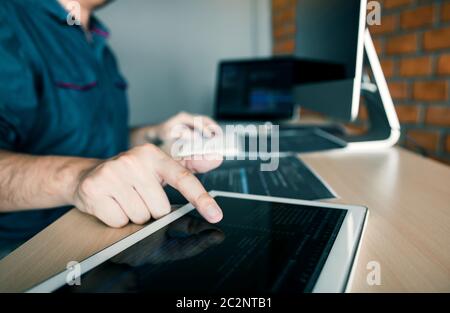 Software developer is pointing to the paper working and analyzing together the code written into the program on the computer. Stock Photo