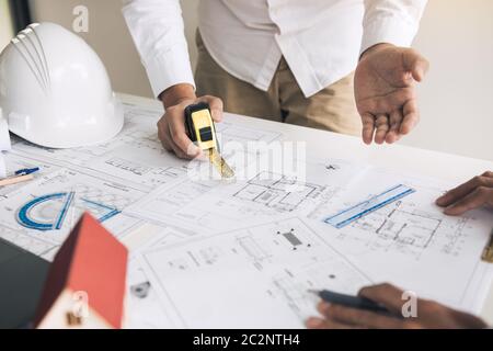 Two partnership architects or engineering working with blueprints and discussing project together at the meeting in the office. Stock Photo