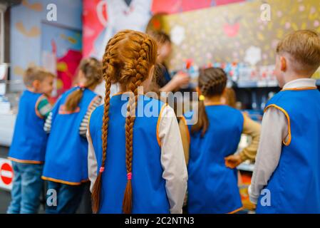 Children in uniform playing salesmen, playroom. Kids plays sellers in imaginary supermarket, salesman profession learning Stock Photo