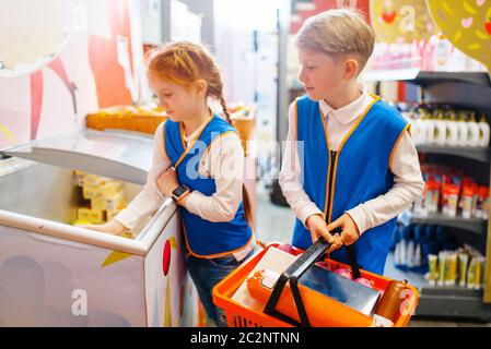 Children in uniform, boy and girl playing salesmen, playroom. Kids plays sellers in imaginary supermarket, salesman occupation learning Stock Photo