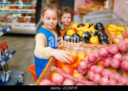 Adorable girl in uniform playing saleswoman, playroom. Kids plays sellers in imaginary supermarket, salesman profession learning Stock Photo