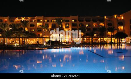 Swimming pool with blue water and night hotel on holidays. People relax in evening near pool Stock Photo