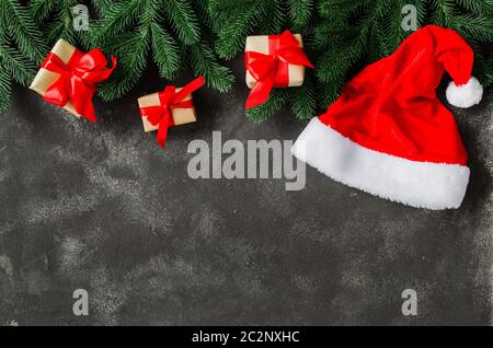 Christmas background with Christmas presents and Santa Claus hat. Christmas gift boxes on dark concrete background. Top view with copy space Stock Photo