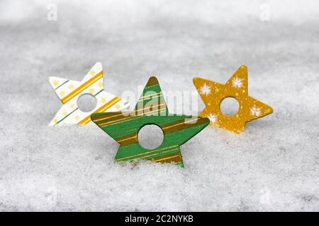 Three colourful wooden Christmas stars in the snow Stock Photo