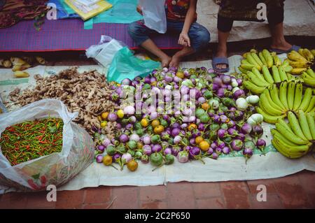 Street vendor selling fresh vegetables in Luang Prabang morning market in Laos Stock Photo