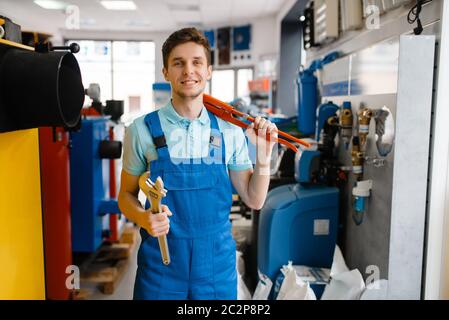Plumber shows pipe wrenches at the showcase in plumbering store. Man buying sanitary engineering tools and equipment in shop Stock Photo