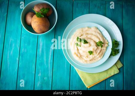 Delicious mashed potatoes with greens in bowl on blue teal wooden table top view Stock Photo