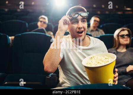 Surprised man with popcorn watching film in cinema. Movie entertainment Stock Photo