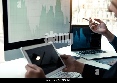 Investor man analyzing the graph of the stock market using a pen pointing to the computer screen. Stock Photo