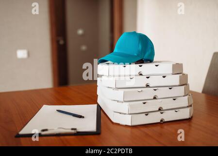 Pizza delivery concept, delivering service, nobody. Pizzeria business, carton boxes, cap and empty blank on the table Stock Photo