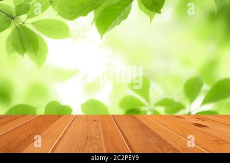 Wood table top on blur abstract green leaf from garden in the morning background. Stock Photo
