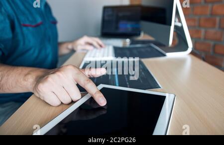Software developer is pointing to the paper working and analyzing together the code written into the program on the computer. Stock Photo