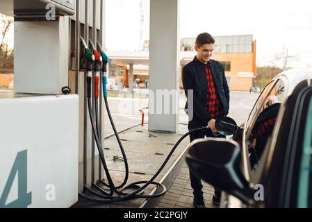 Man with gun fuels vehicle on gas station, fuel filling. Petrol fueling, gasoline or diesel refuel service Stock Photo
