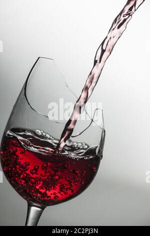 Red wine pourin in a broken wine glass Stock Photo