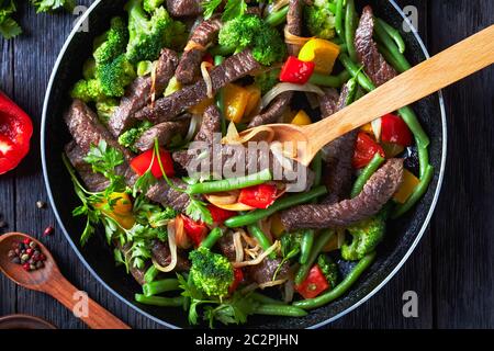 Mexican cuisine: roasted beef fajita strips with summer vegetables: yellow and red sweet peppers, parsley, onion, green beans, and broccoli served on Stock Photo