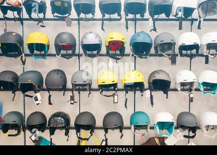 Rows of ski and snowboarding helmets in sports shop, nobody. Winter active leisure, showcase with protect equipment Stock Photo