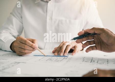 Two partnership architects or engineering working with blueprints and discussing project together at the meeting in the office. Stock Photo
