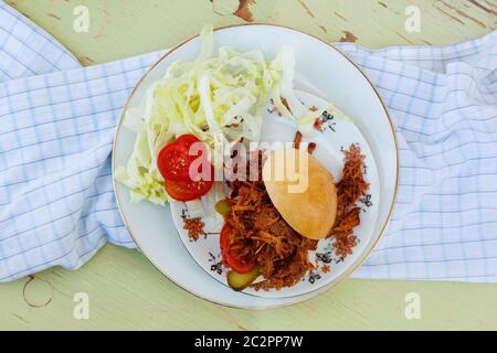 Pulled pork burger on plate in sunny day from above. Party food background. Stock Photo