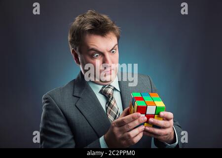 Businessman looking at  rubik cube in his hands Stock Photo