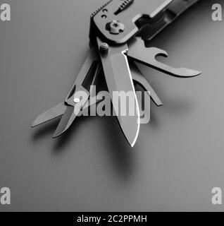 Black opened multitool knife on grey Stock Photo