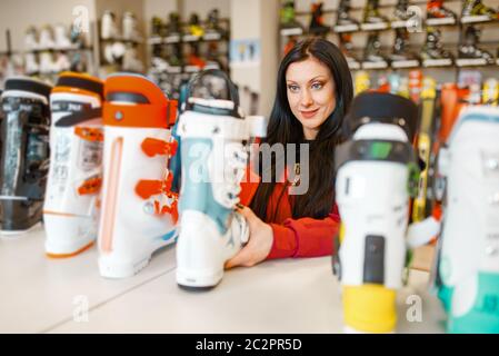 Female person at the showcase choosing ski or snowboarding boots, shopping in sports shop. Winter season extreme lifestyle, active leisure store, cust Stock Photo