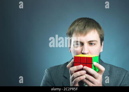 Businessman looking at  rubik cube in his hands Stock Photo