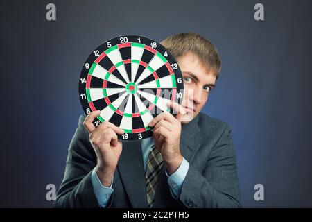 Businessman holding darts board in his hands isolated on gray Stock Photo