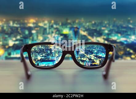 Night cityscape focused in glasses lenses. Vision concept Stock Photo