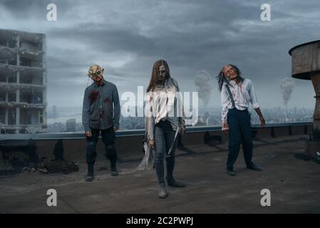 Scary zombie army on the roof of abandoned building, deadly chase. Horror in city, creepy crawlies attack, apocalypse Stock Photo