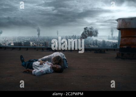 Zombie couple on the roof of abandoned building, deadly chase. Horror in city, creepy crawlies attack, apocalypse Stock Photo